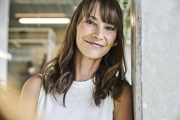 Beautiful woman smiling while leaning on wall at home